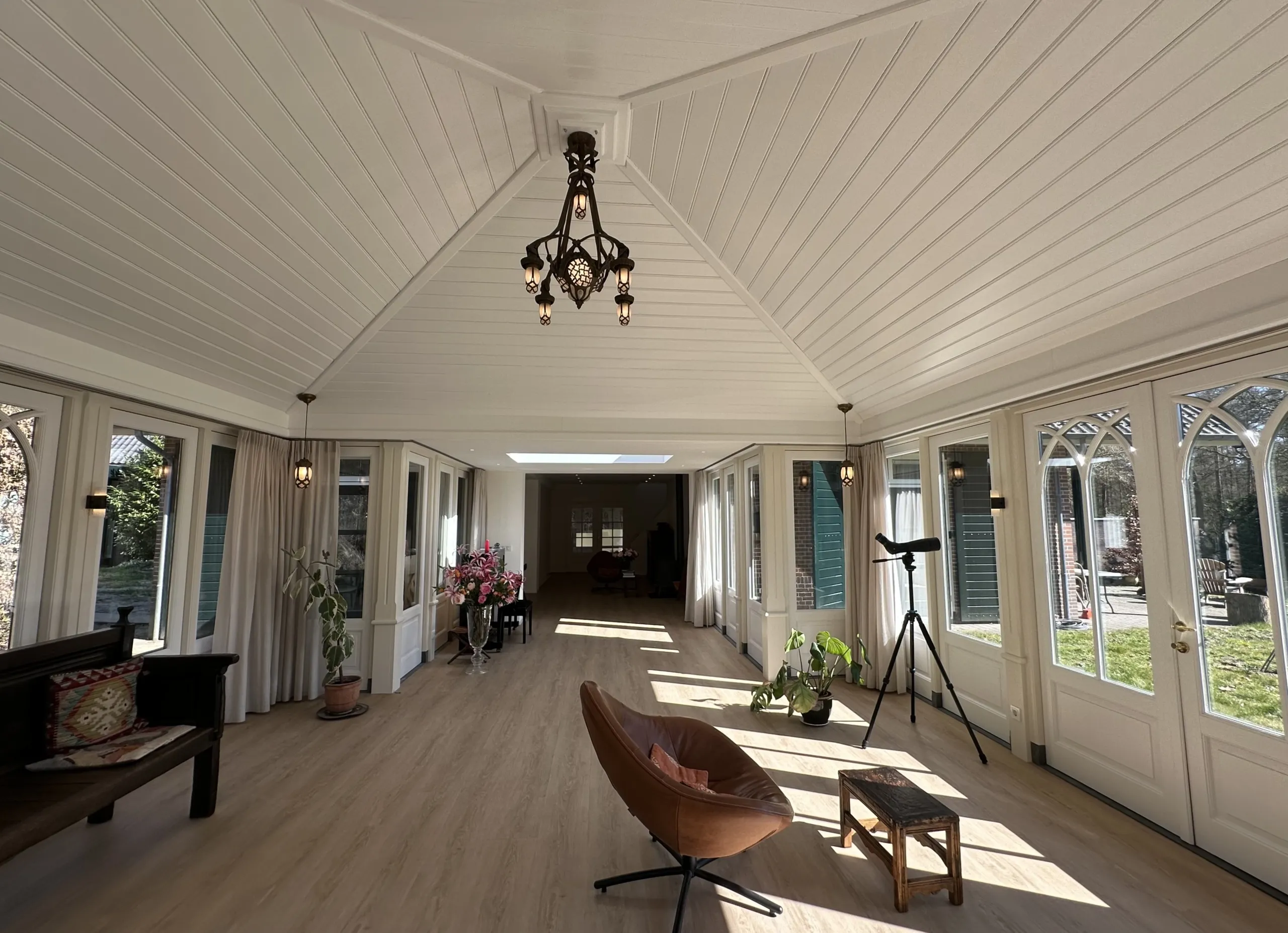 Lichte, warme serre met houten vloer en bronzen kroonluchter — interieurproject van BuroGo